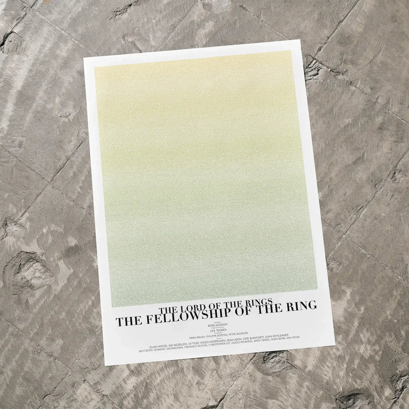 A The Lord of the Rings: The Fellowship of the Ring movie script poster laid flat on a textured floor surface.
