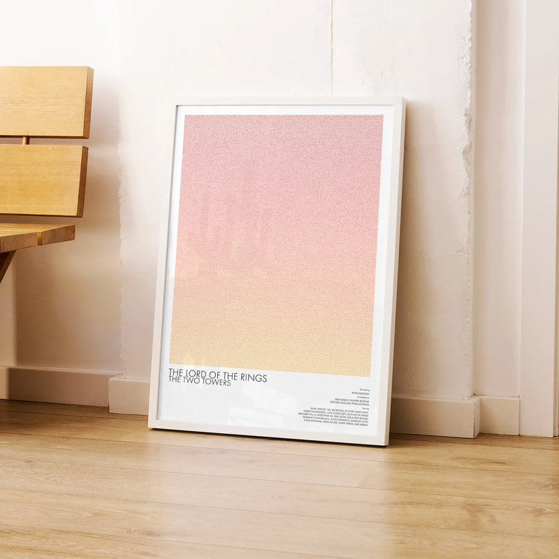 A framed The Lord of the Rings: The Two Towers movie script poster leaning against a wall in a modern interior.
