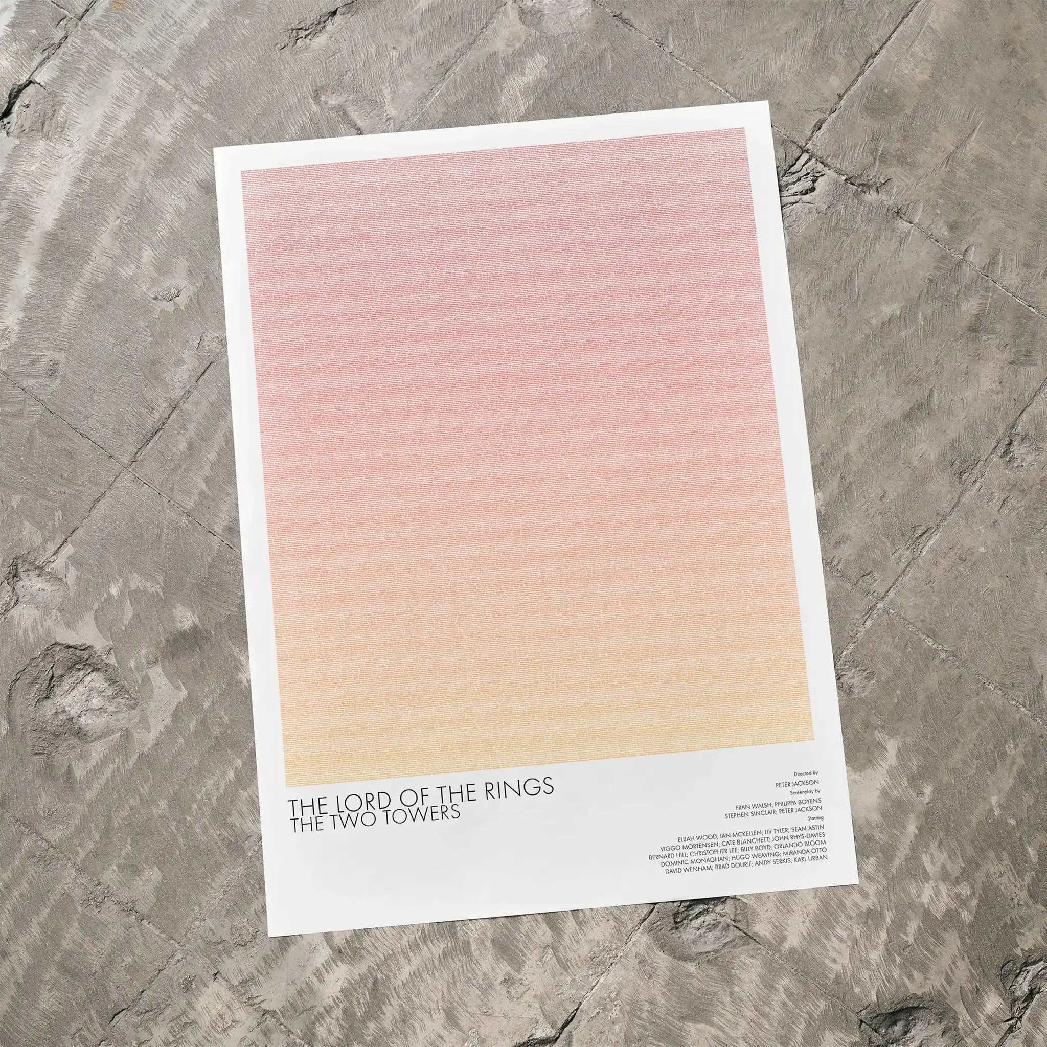 A The Lord of the Rings: The Two Towers movie script poster laid flat on a textured floor surface.