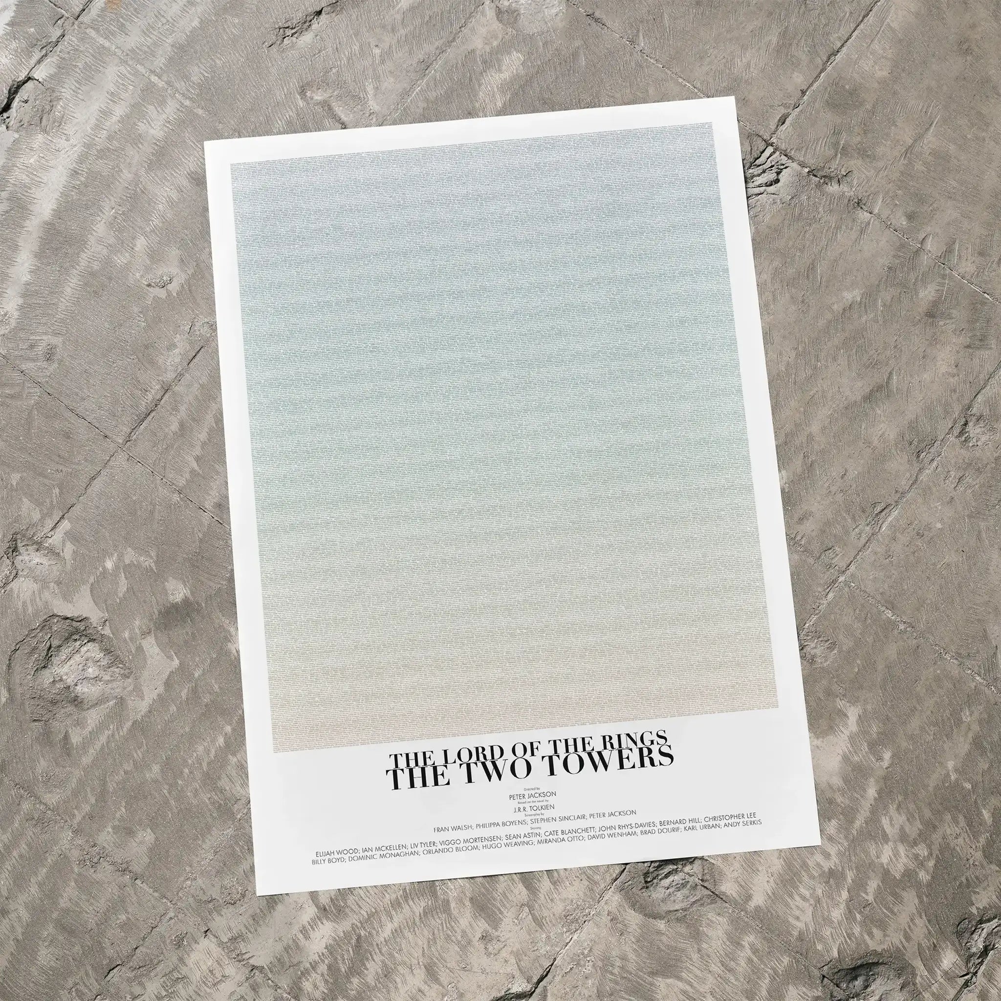 A The Lord of the Rings: The Two Towers movie script poster laid flat on a textured floor surface.