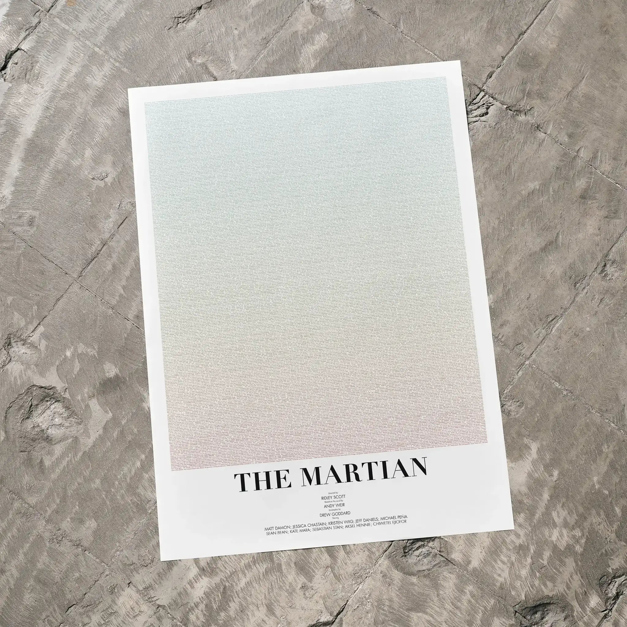 A The Martian movie script poster laid flat on a textured floor surface.