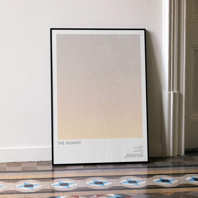 A framed The Mummy movie script poster leaning against a wall in a minimalist interior.