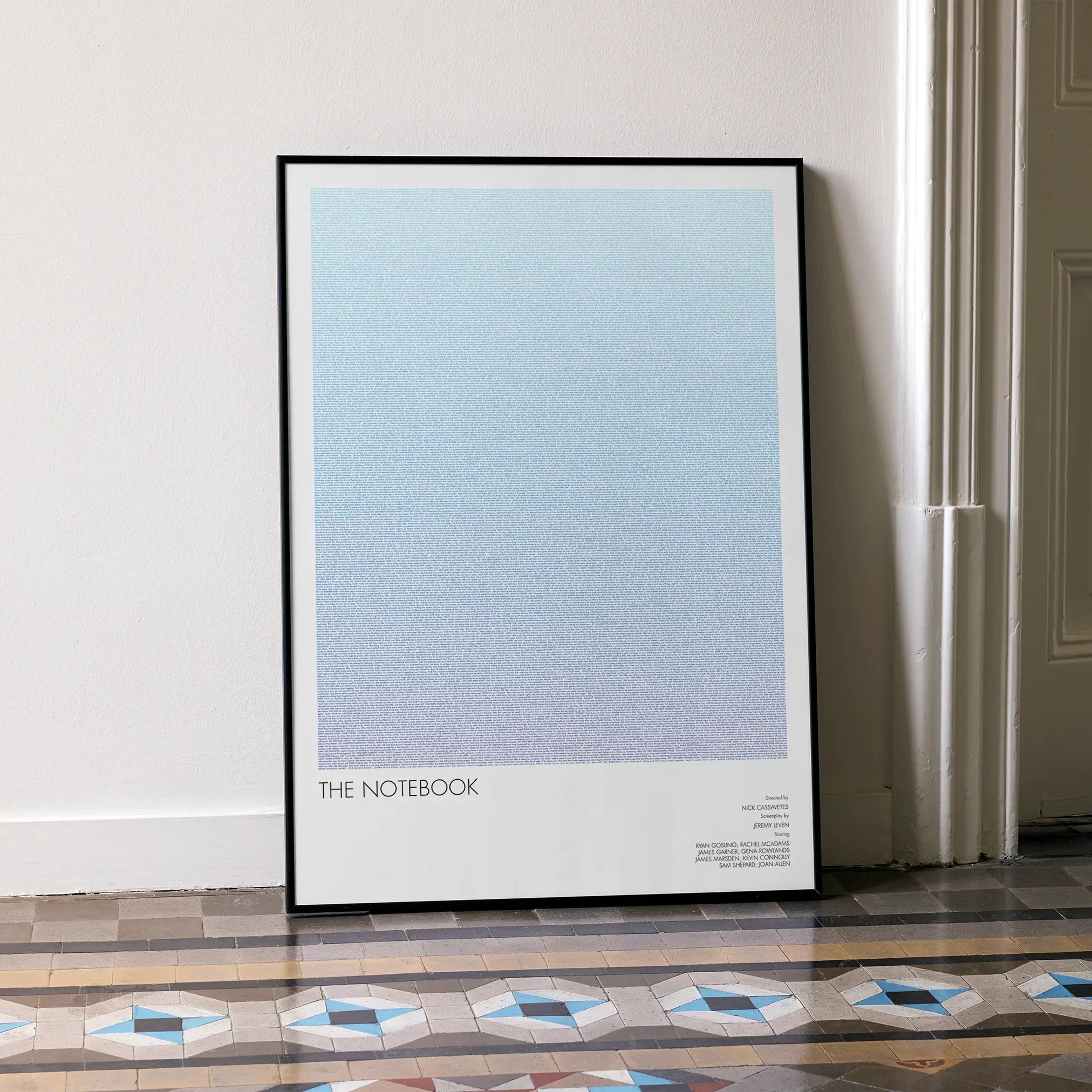 A framed The Notebook movie script poster leaning against a wall in a minimalist interior.