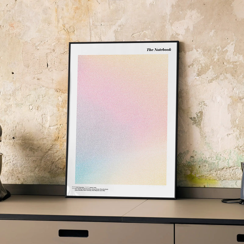 A framed The Notebook movie script poster displayed on a cabinet in a minimalist interior.