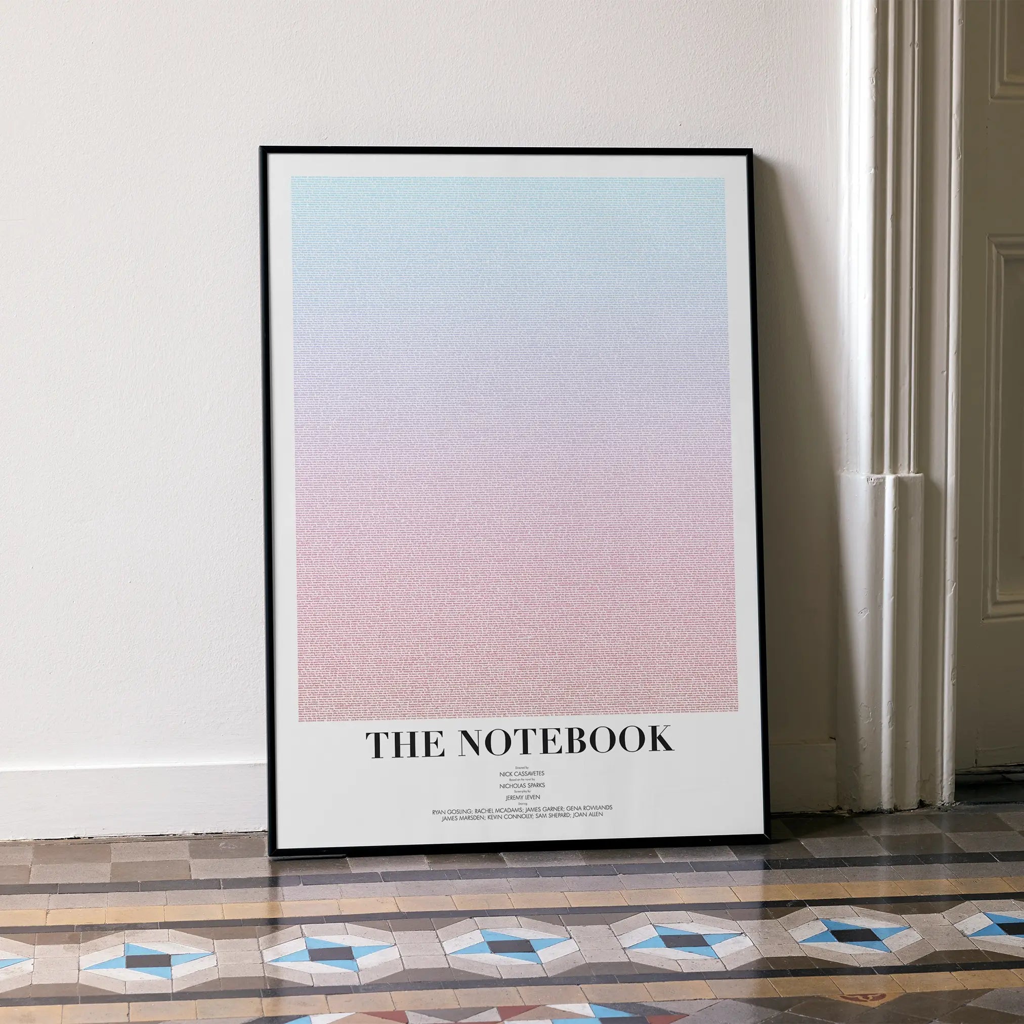 A framed The Notebook movie script poster leaning against a wall in a minimalist interior.