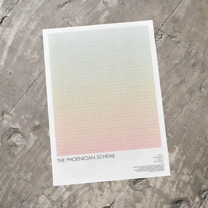 A The Phoenician Scheme movie script poster laid flat on a textured floor surface.