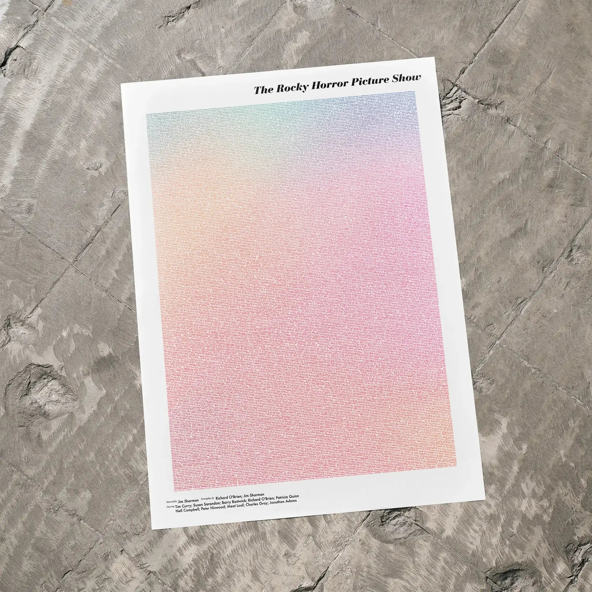 A The Rocky Horror Picture Show movie script poster laid flat on a textured floor surface.