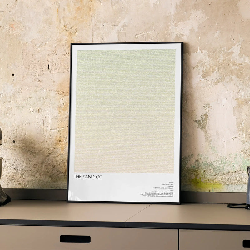 A framed The Sandlot movie script poster displayed on a cabinet in a minimalist interior.
