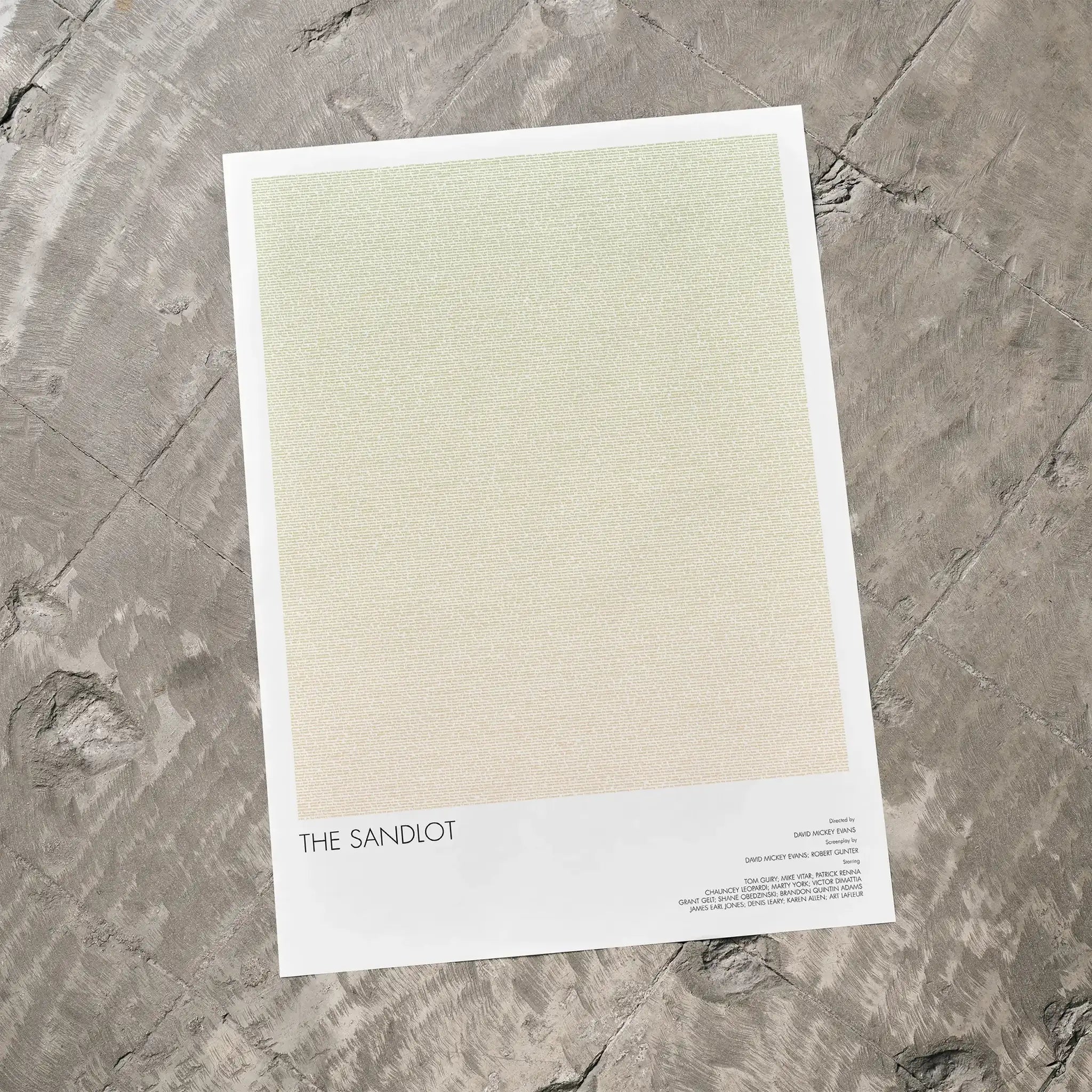 A The Sandlot movie script poster laid flat on a textured floor surface.