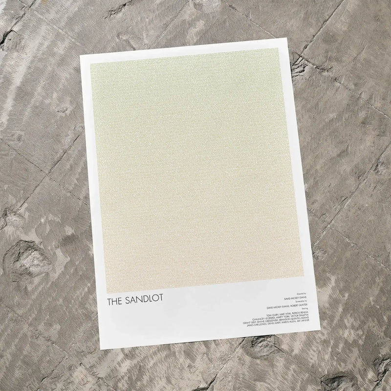 A The Sandlot movie script poster laid flat on a textured floor surface.