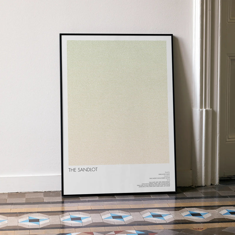 A framed The Sandlot movie script poster leaning against a wall in a minimalist interior.