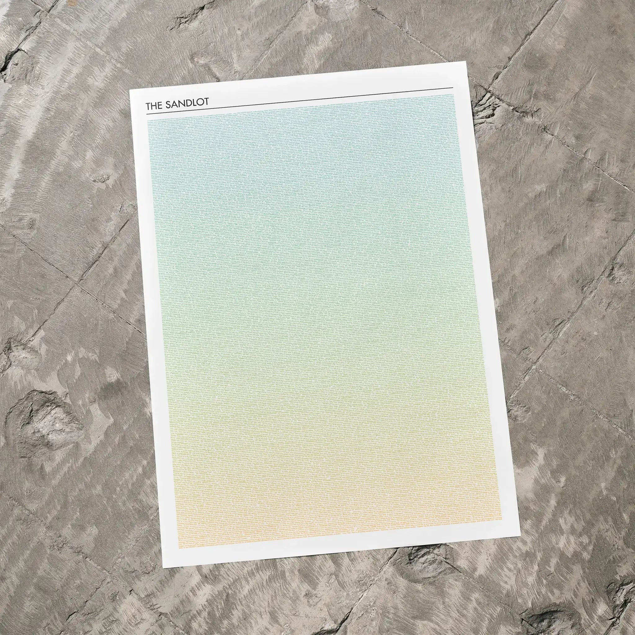 A The Sandlot movie script poster laid flat on a textured floor surface.