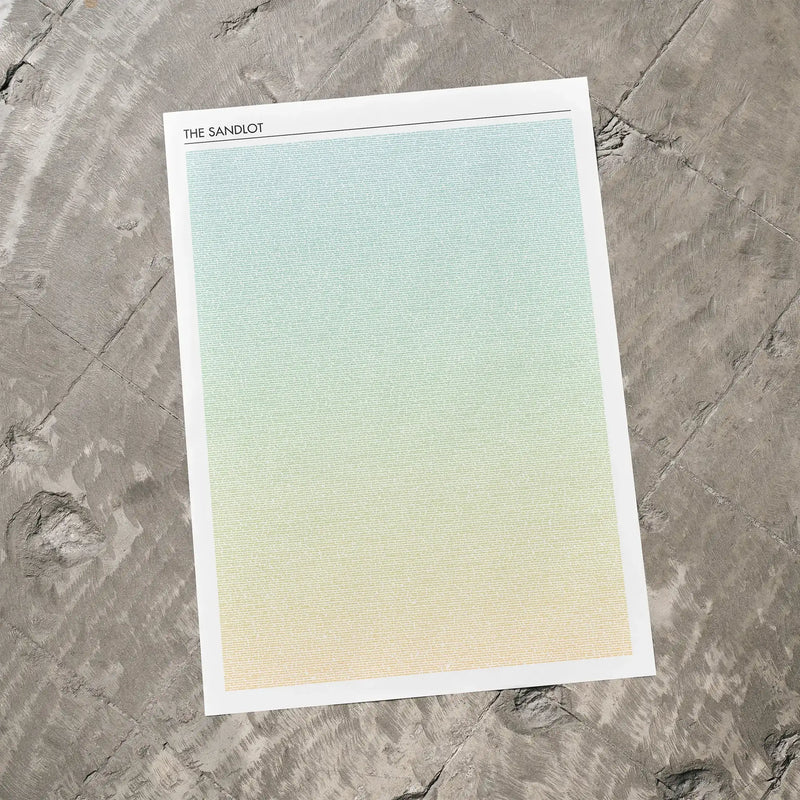 A The Sandlot movie script poster laid flat on a textured floor surface.