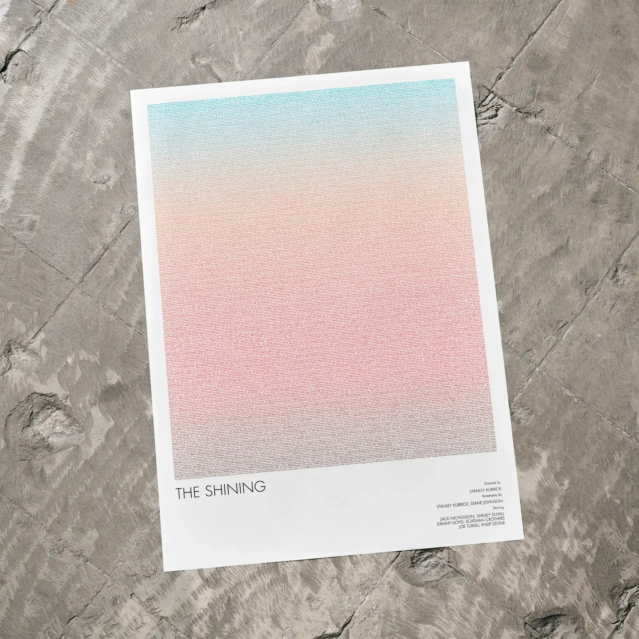 A The Shining movie script poster laid flat on a textured floor surface.
