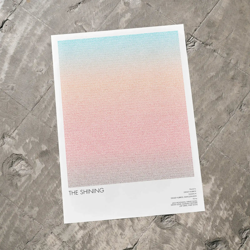 A The Shining movie script poster laid flat on a textured floor surface.