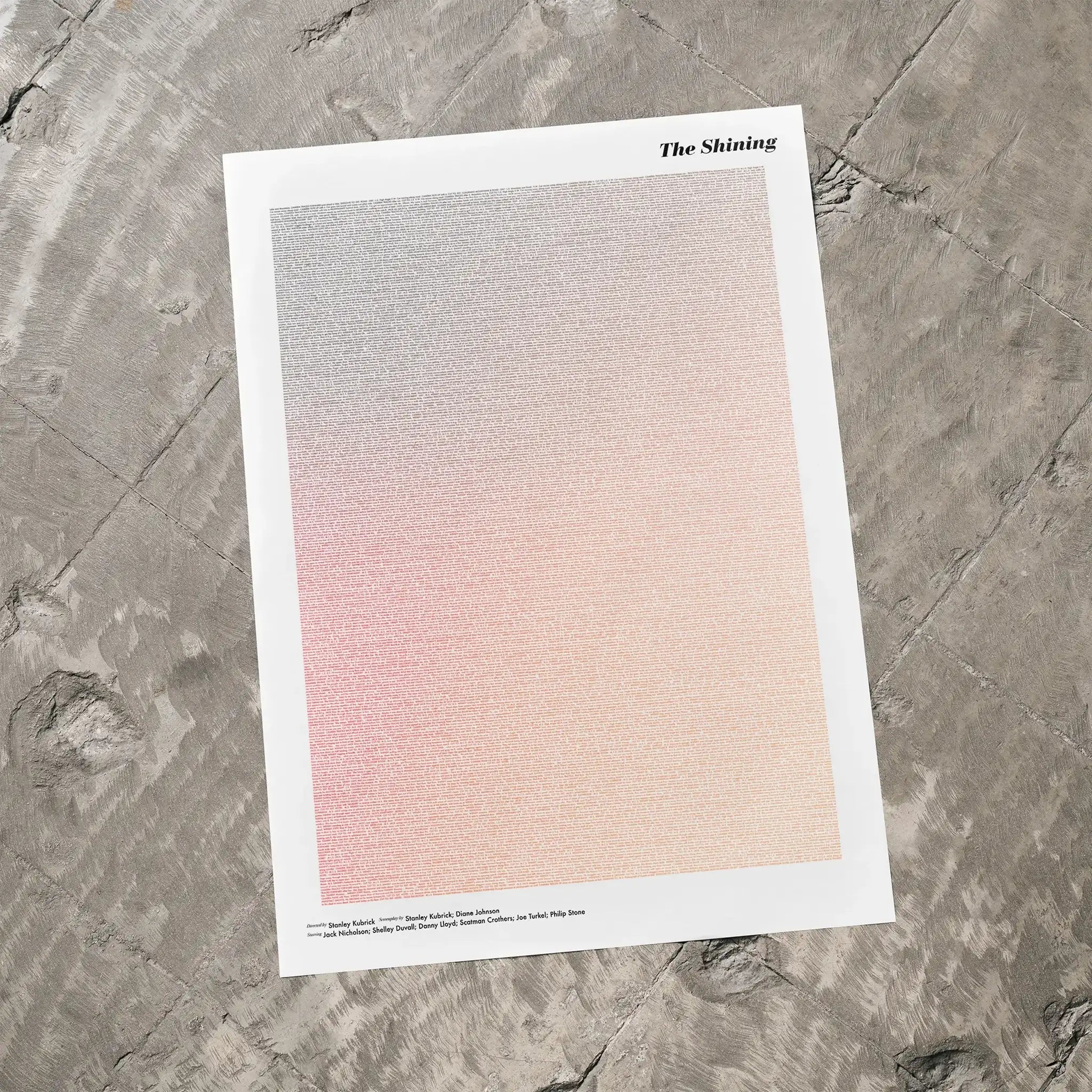 A The Shining movie script poster laid flat on a textured floor surface.