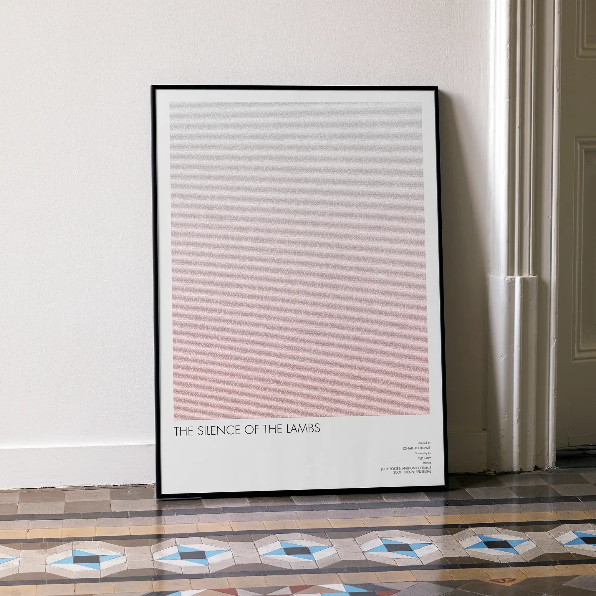 A framed The Silence of the Lambs movie script poster leaning against a wall in a minimalist interior.