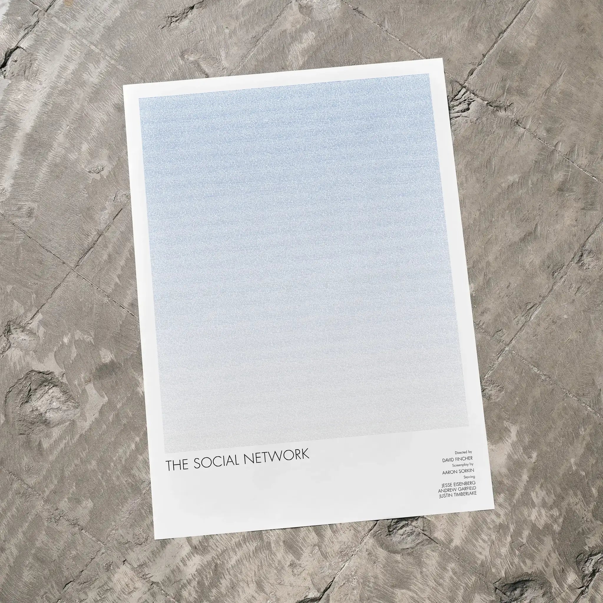 A The Social Network movie script poster laid flat on a textured floor surface.