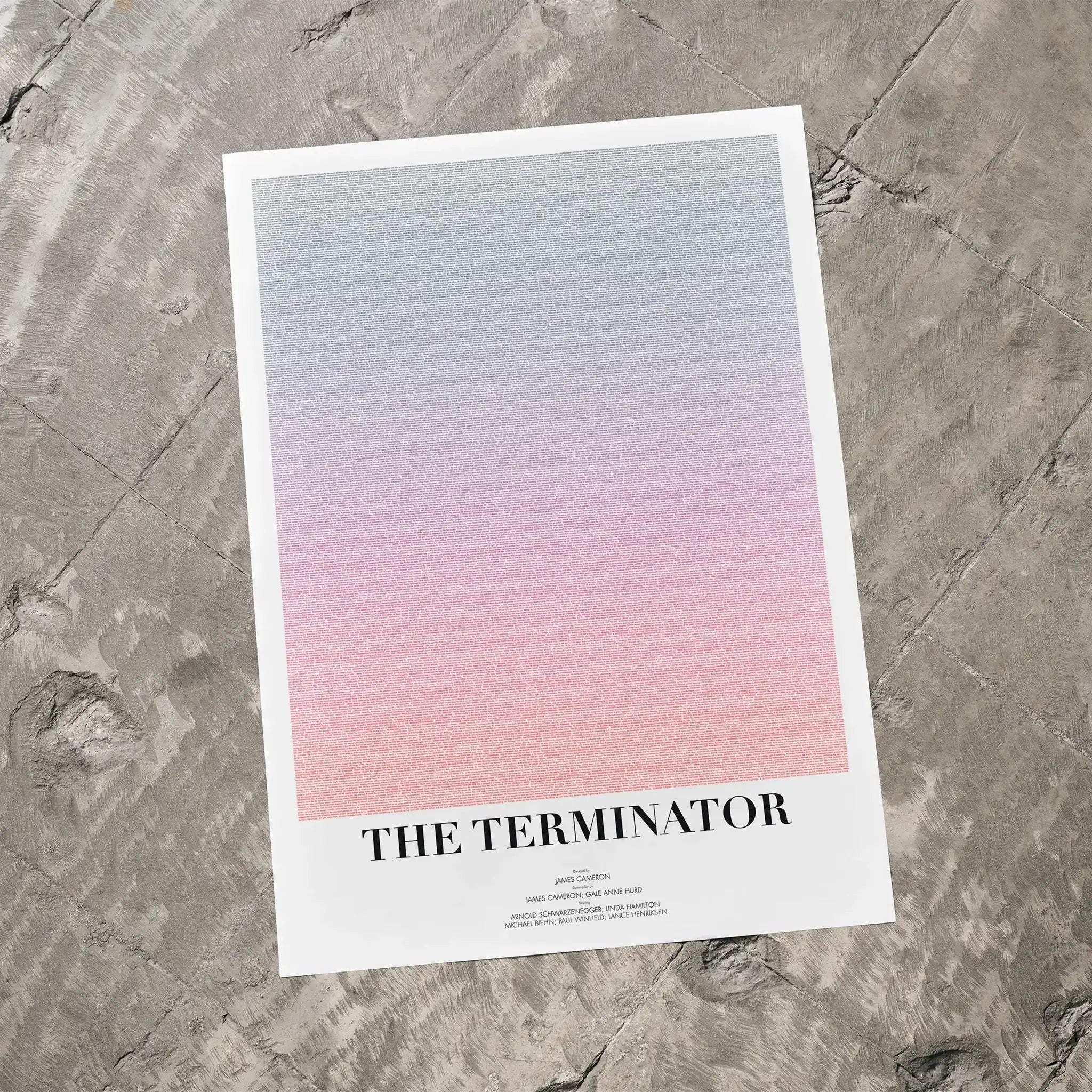 A The Terminator movie script poster laid flat on a textured floor surface.