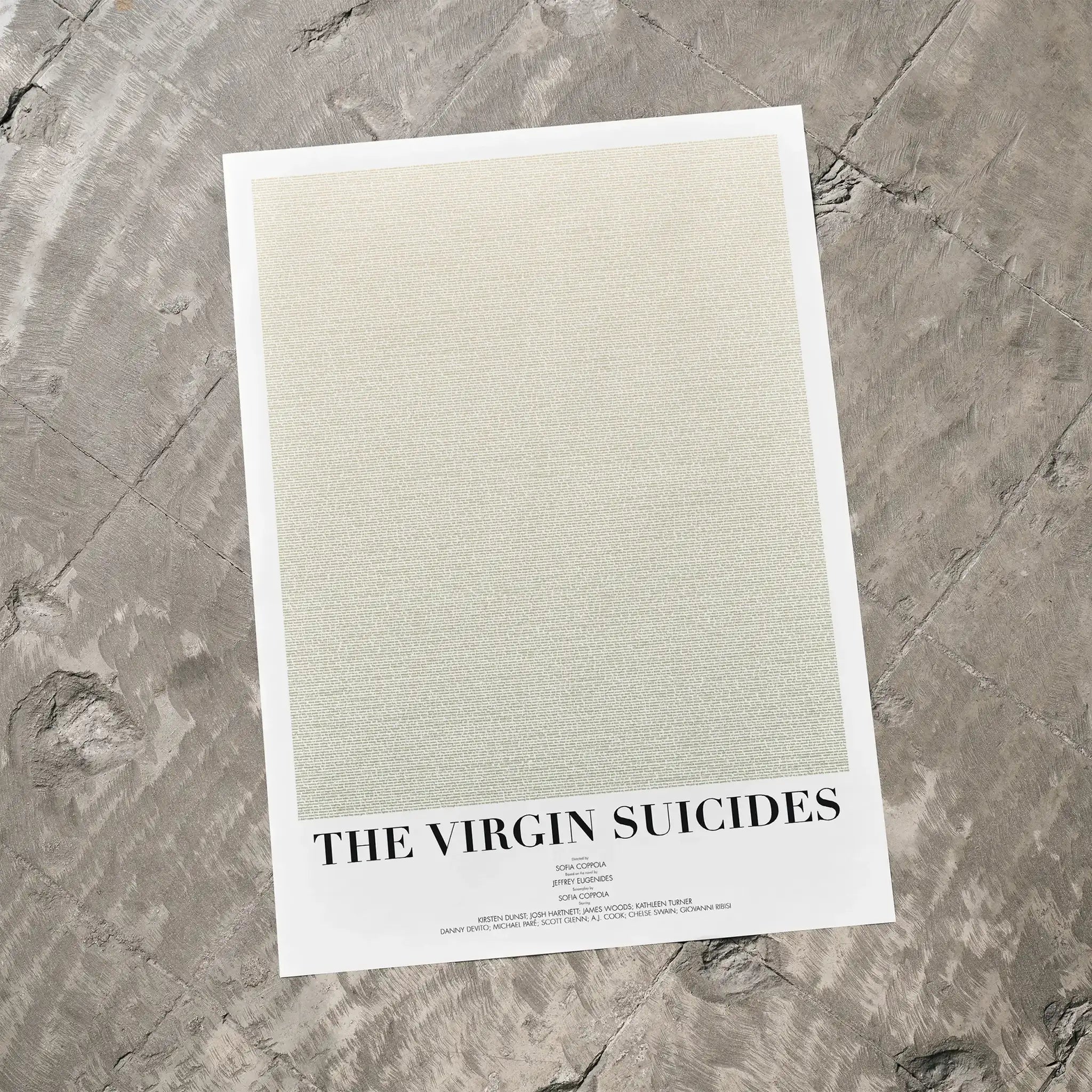 A The Virgin Suicides movie script poster laid flat on a textured floor surface.
