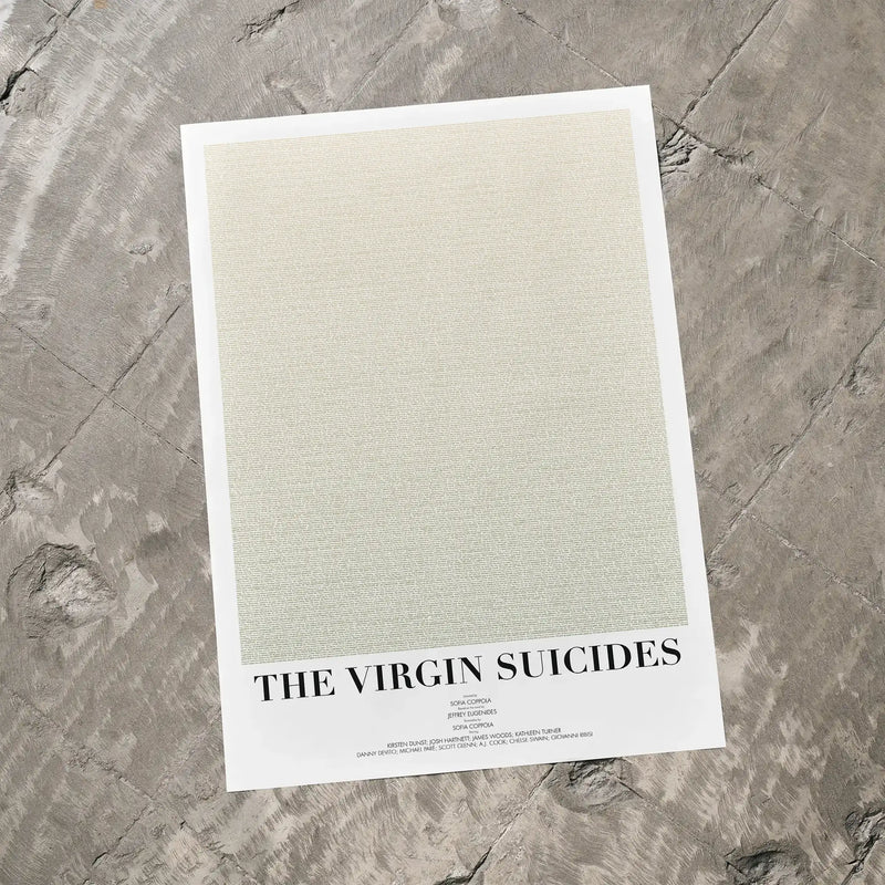 A The Virgin Suicides movie script poster laid flat on a textured floor surface.