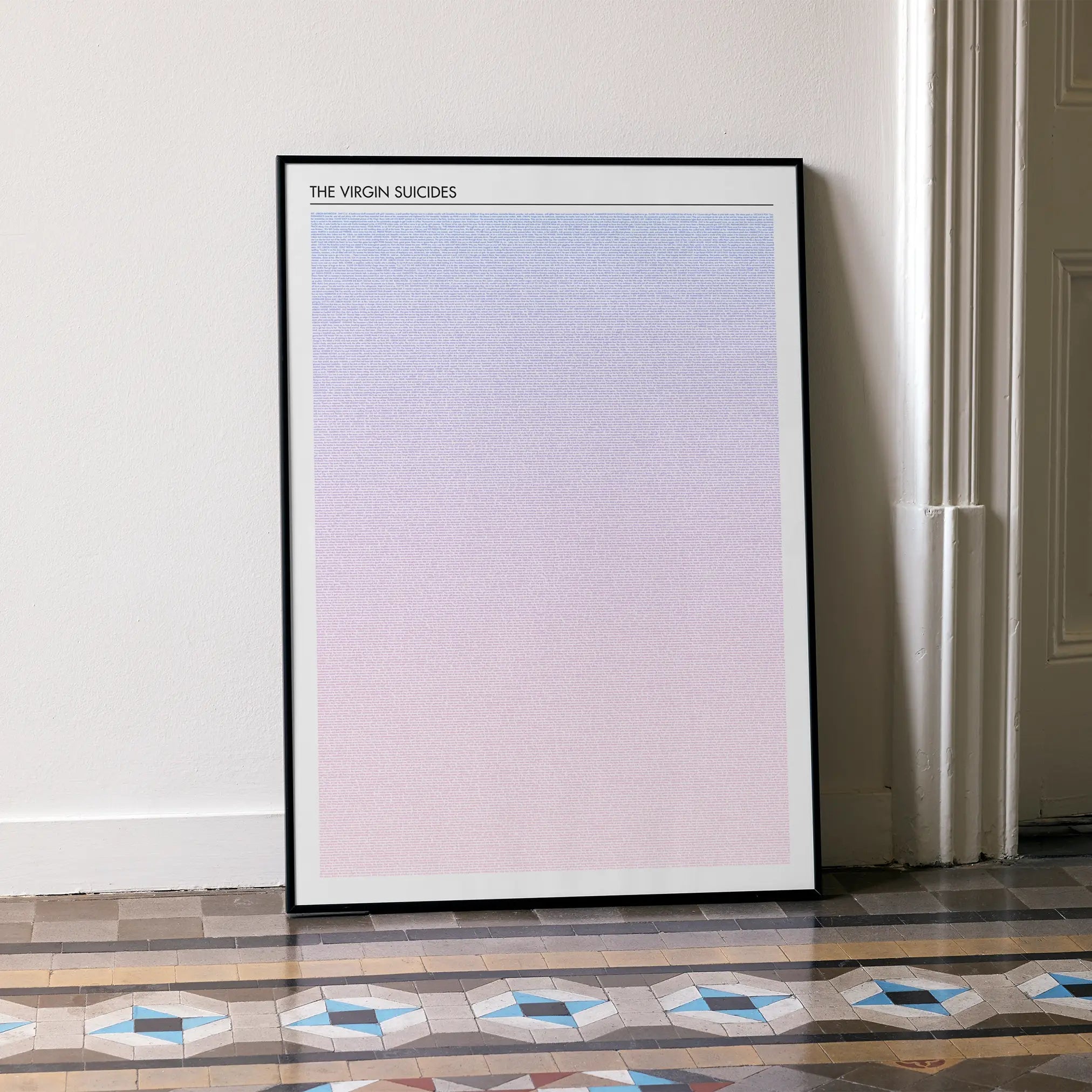 A framed The Virgin Suicides movie script poster leaning against a wall in a minimalist interior.