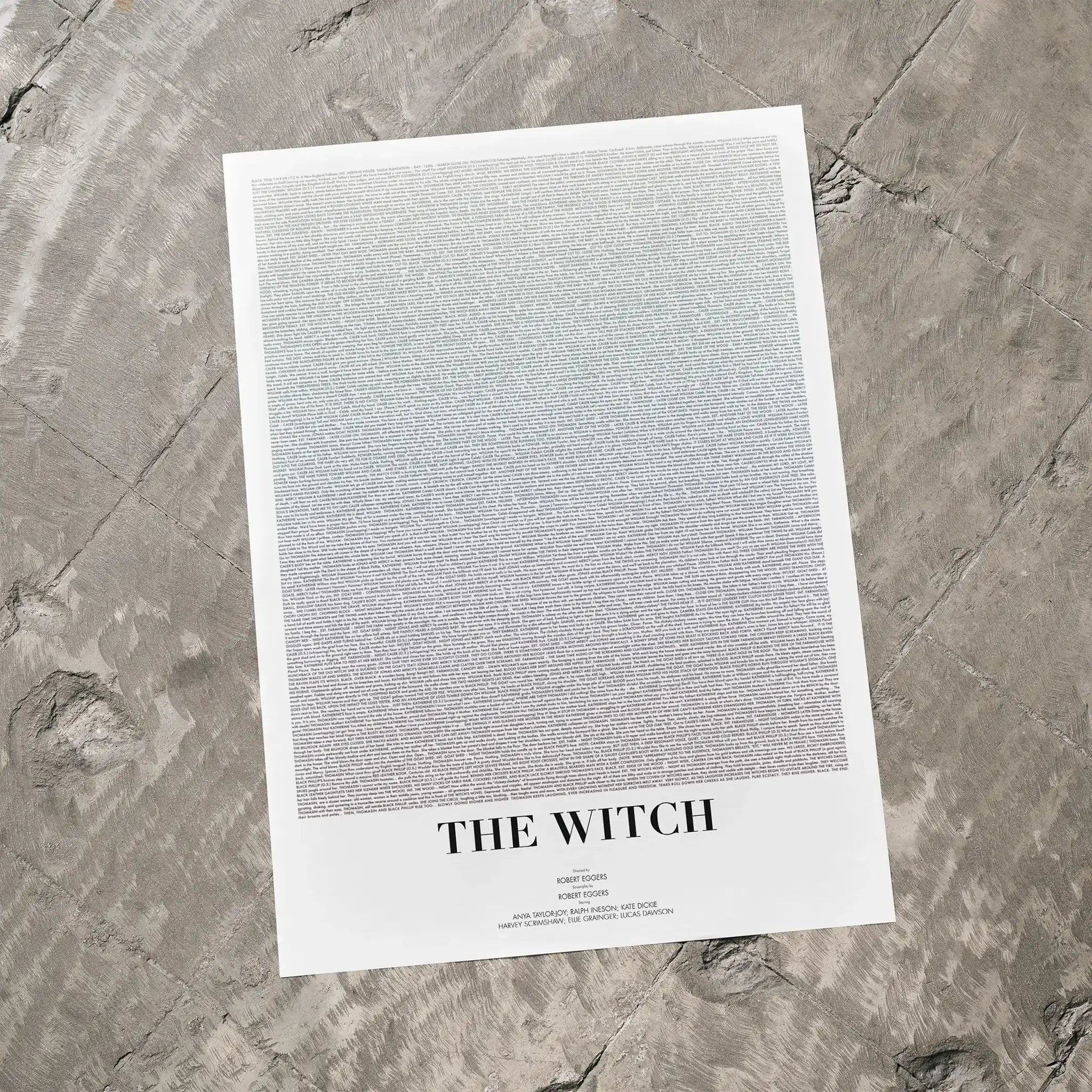 A The Witch movie script poster laid flat on a textured floor surface.