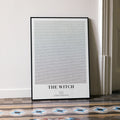A framed The Witch movie script poster leaning against a wall in a minimalist interior.