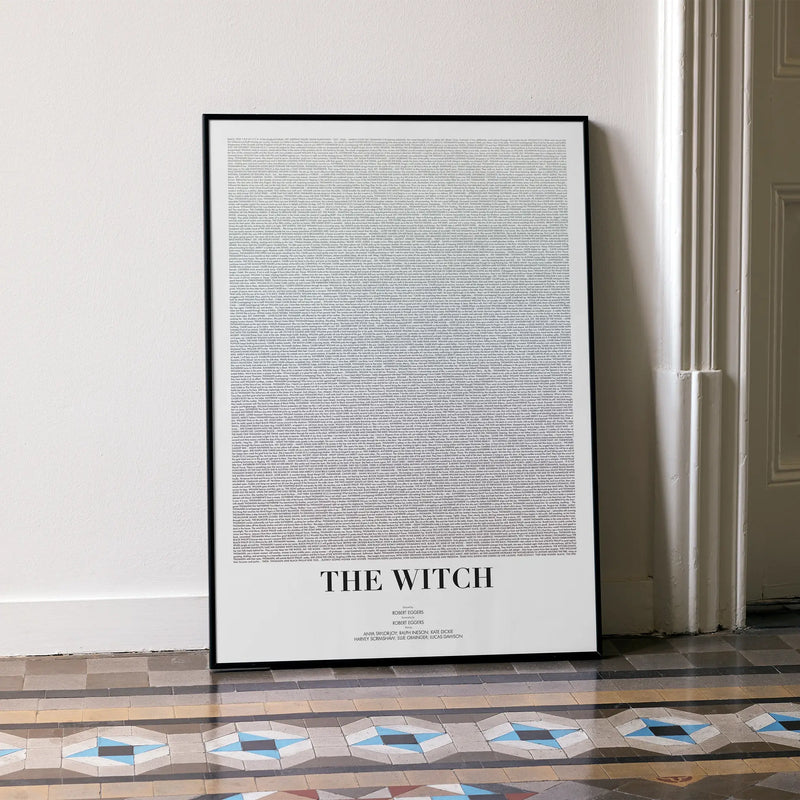 A framed The Witch movie script poster leaning against a wall in a minimalist interior.