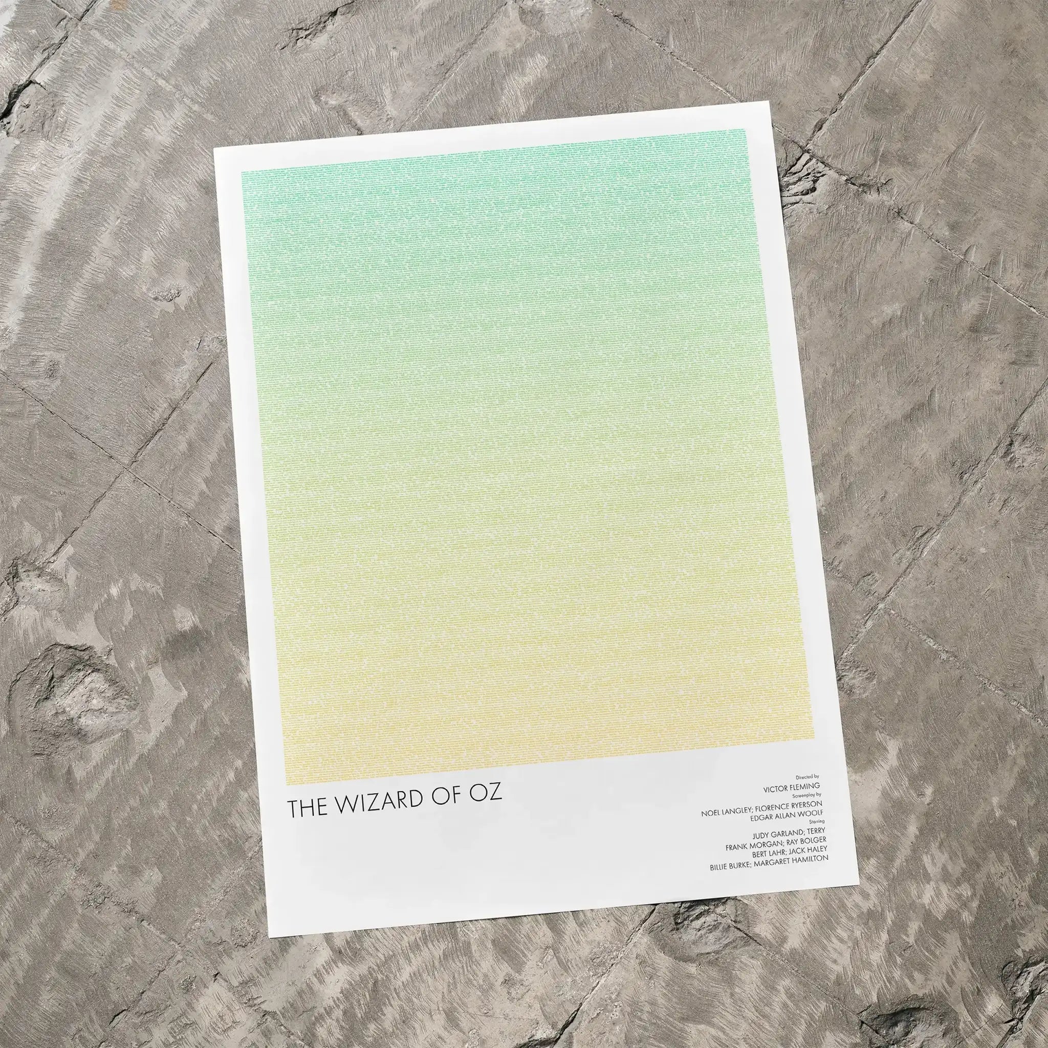 A The Wizard of Oz movie script poster laid flat on a textured floor surface.