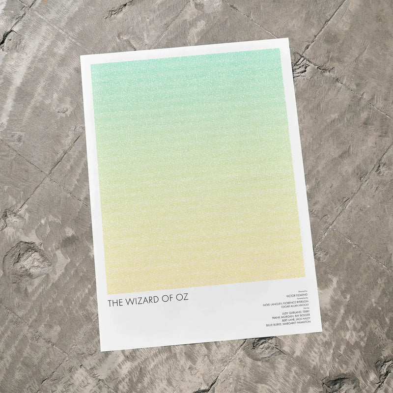 A The Wizard of Oz movie script poster laid flat on a textured floor surface.