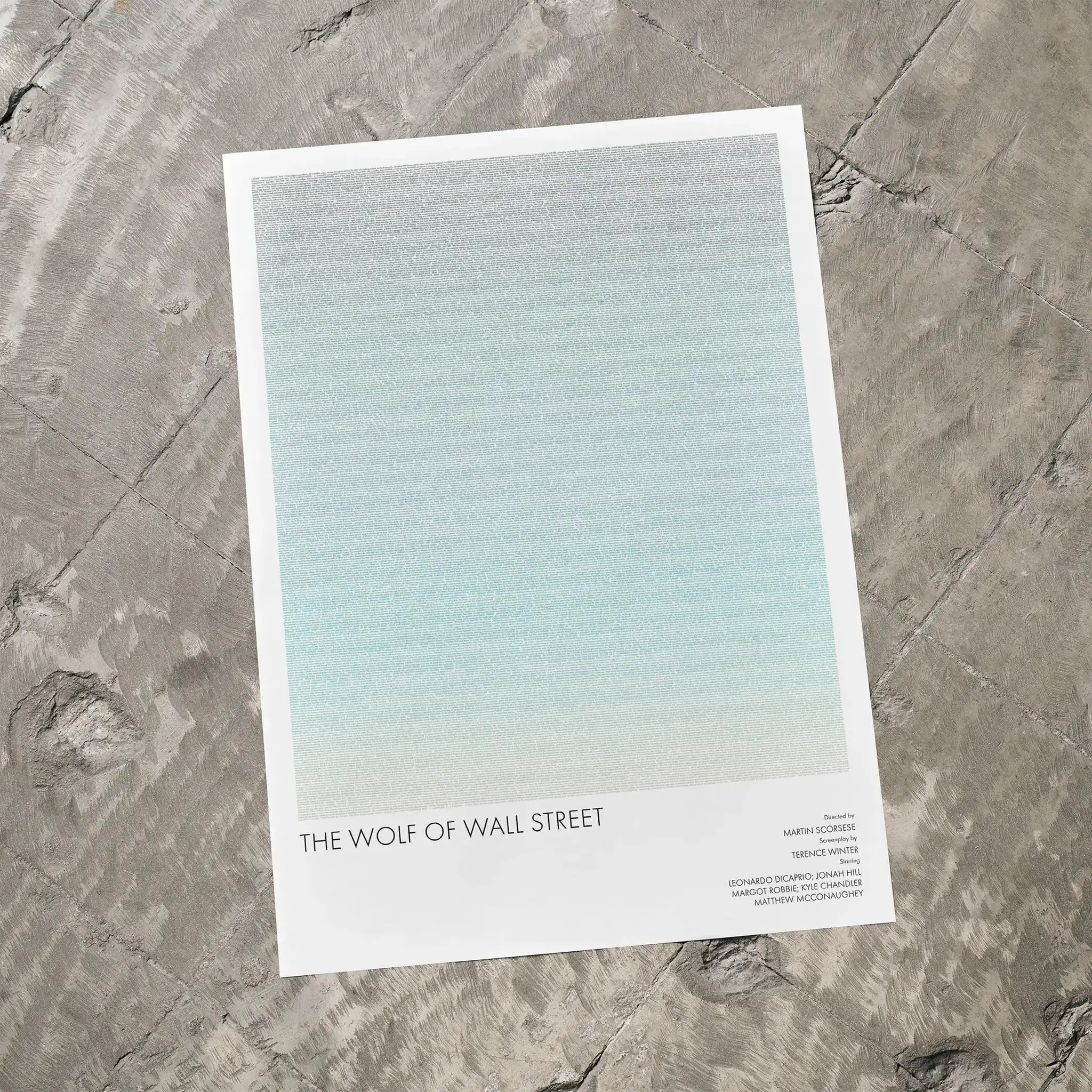 A The Wolf of Wall Street movie script poster laid flat on a textured floor surface.