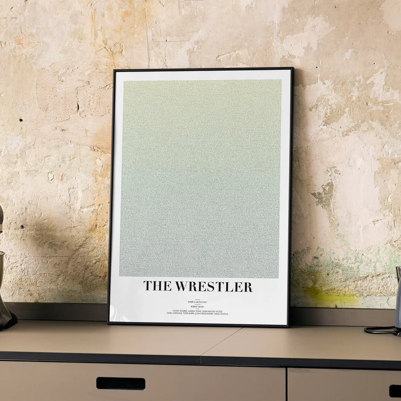 A framed The Wrestler movie script poster displayed on a cabinet in a minimalist interior.