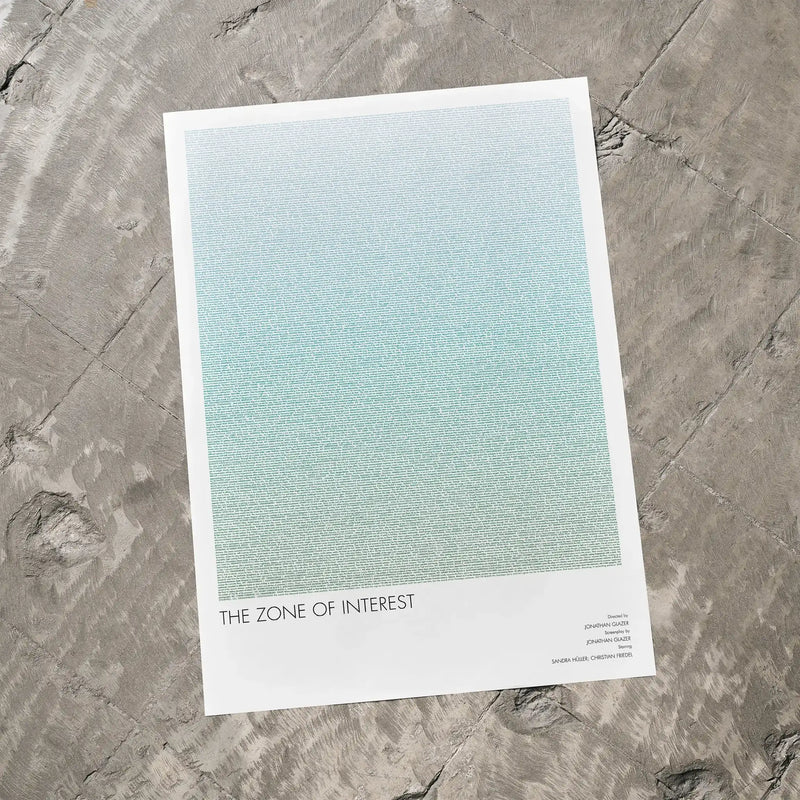 A The Zone of Interest movie script poster laid flat on a textured floor surface.
