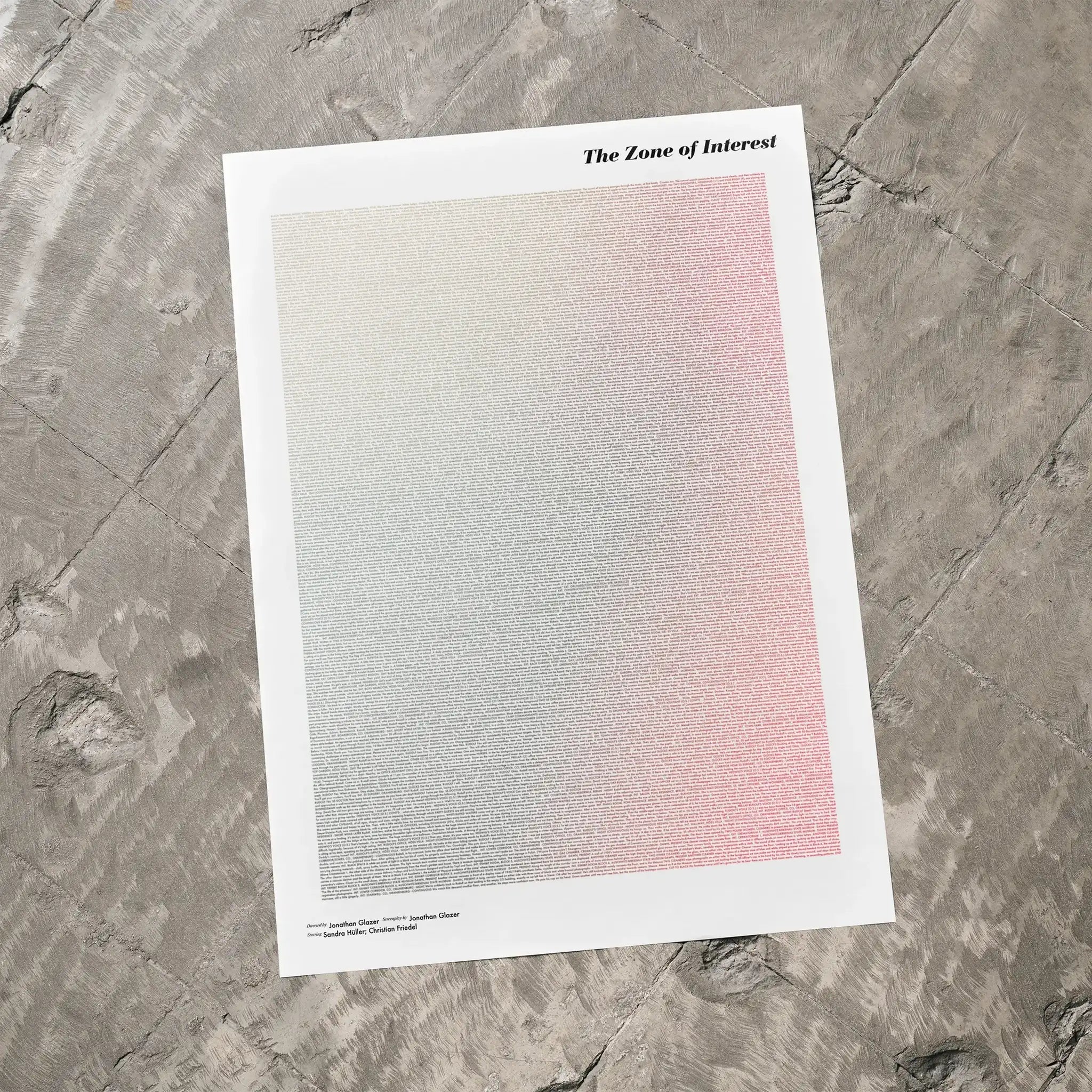 A The Zone of Interest movie script poster laid flat on a textured floor surface.