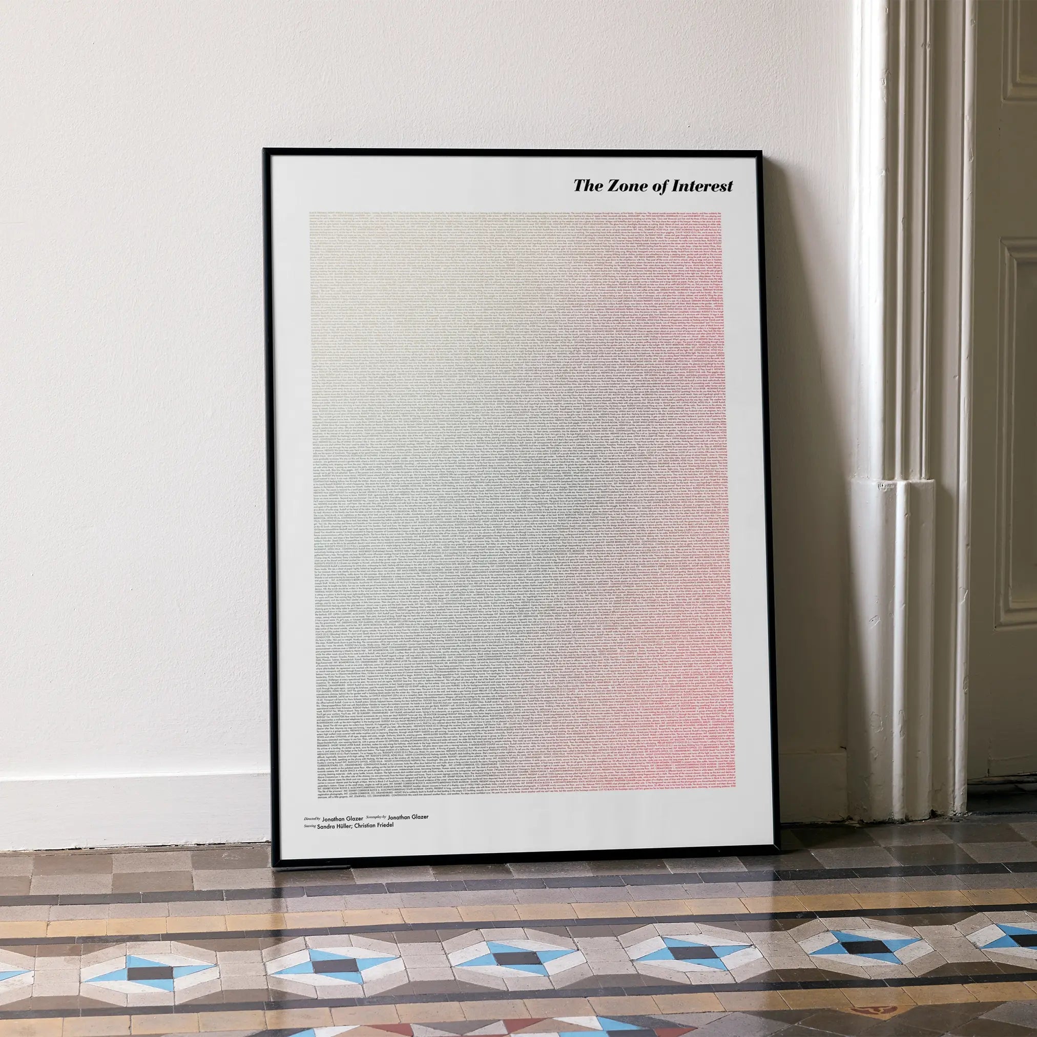 A framed The Zone of Interest movie script poster leaning against a wall in a minimalist interior.