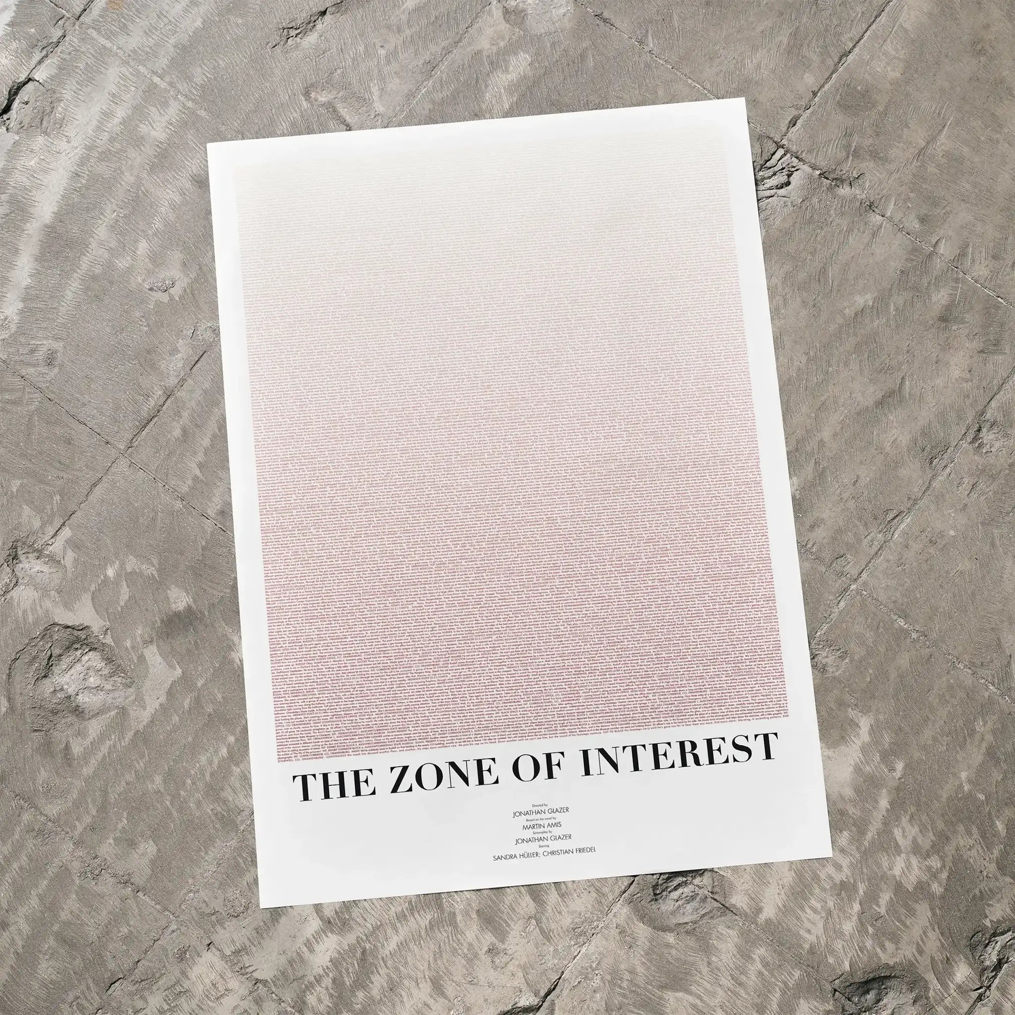 A The Zone of Interest movie script poster laid flat on a textured floor surface.