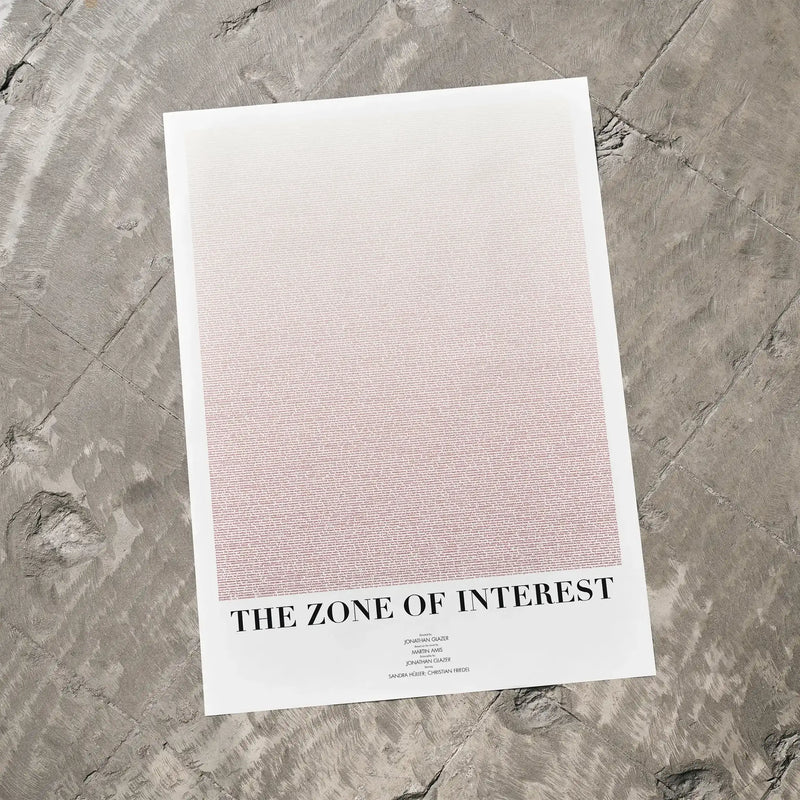 A The Zone of Interest movie script poster laid flat on a textured floor surface.