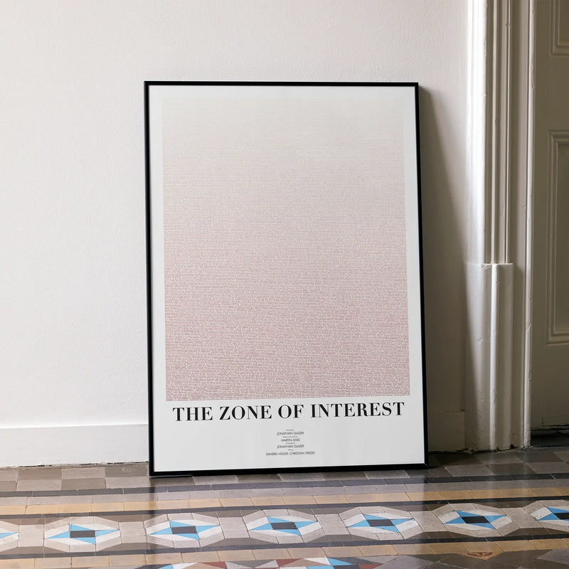 A framed The Zone of Interest movie script poster leaning against a wall in a minimalist interior.