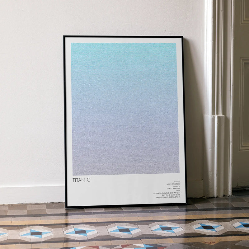 A framed Titanic movie script poster leaning against a wall in a minimalist interior.