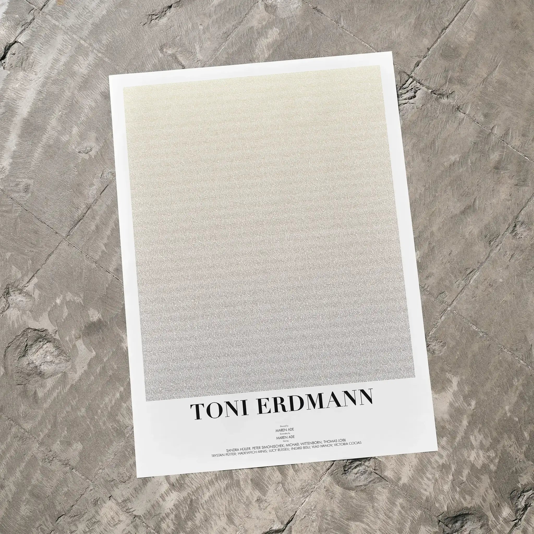 A Toni Erdmann movie script poster laid flat on a textured floor surface.