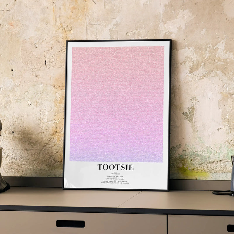 A framed Tootsie movie script poster displayed on a cabinet in a minimalist interior.