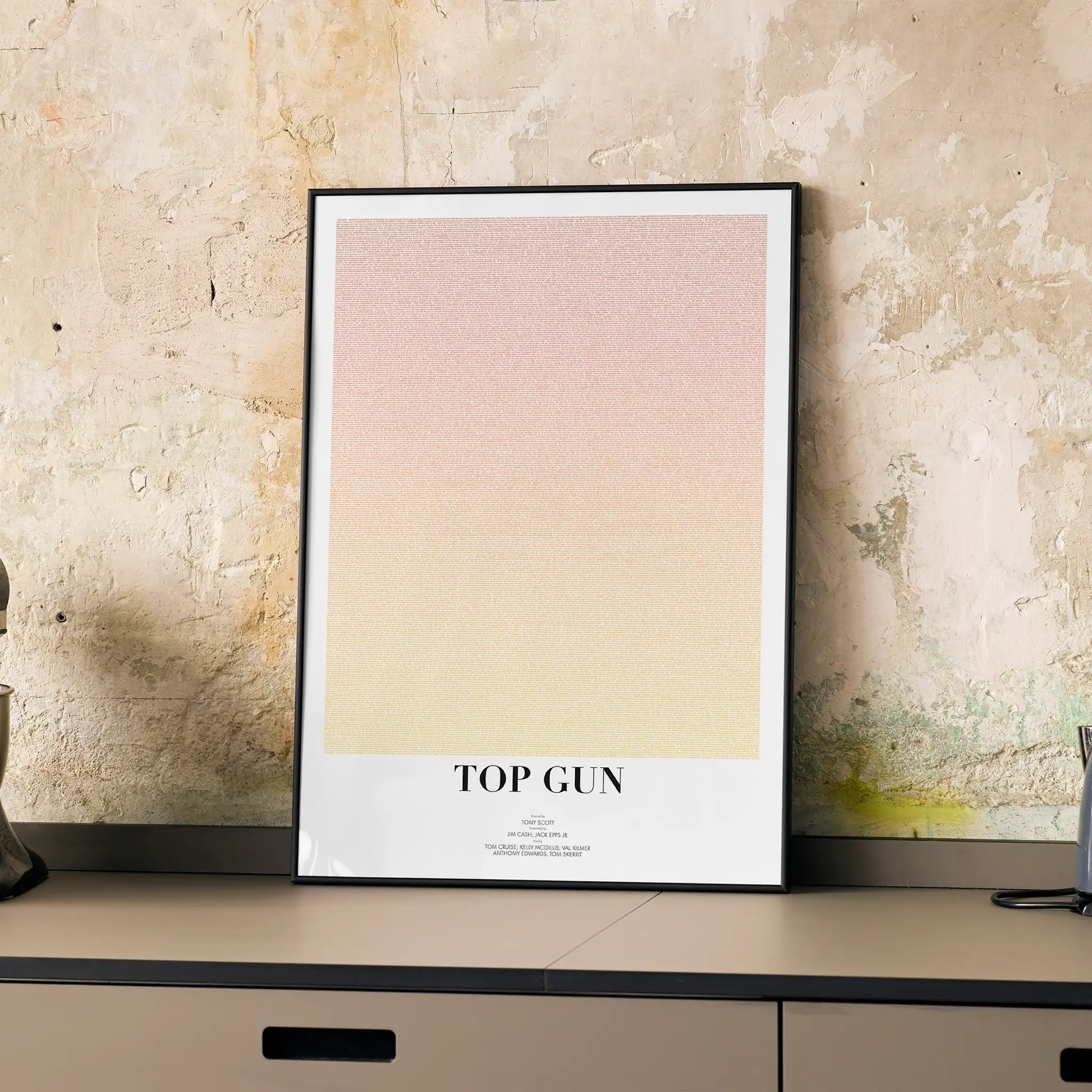 Framed poster with 'Top Gun' text on a textured wall
