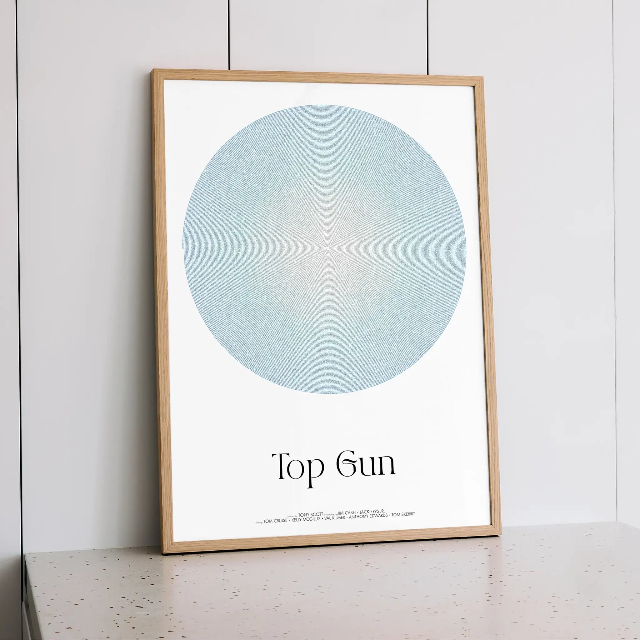 Framed artwork with a blue circle and text 'Top Gun' on a white background