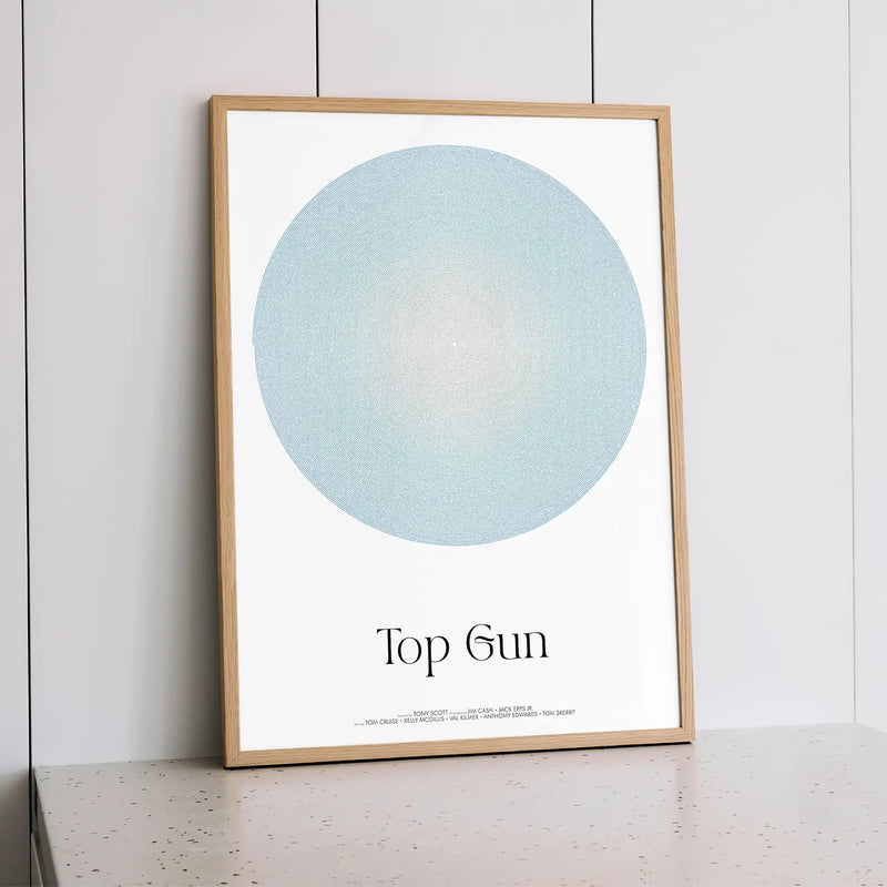 Framed artwork with a blue circle and text 'Top Gun' on a white background