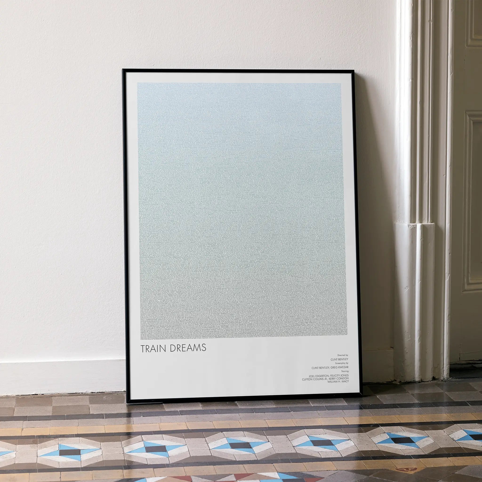 A framed Train Dreams movie script poster leaning against a wall in a minimalist interior.