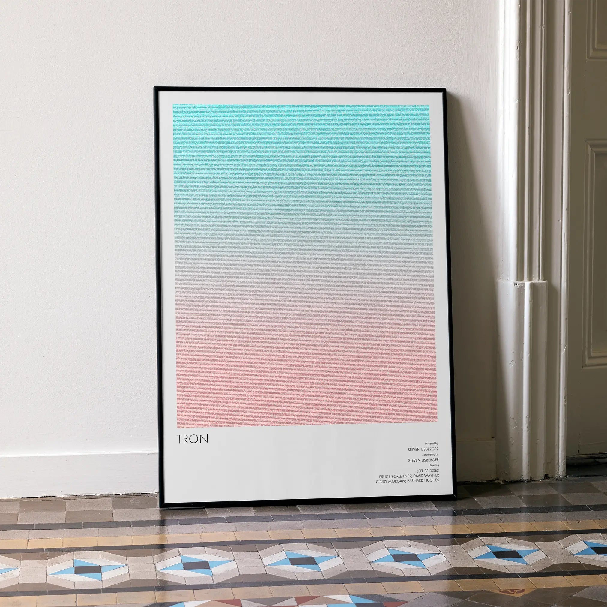 A framed Tron movie script poster leaning against a wall in a minimalist interior.