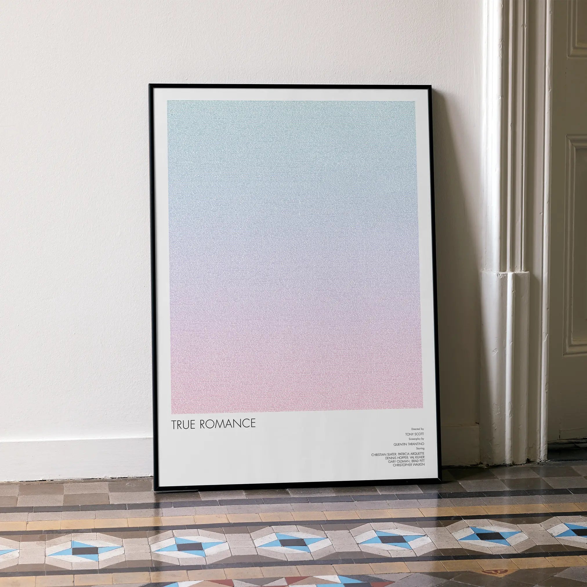 A framed True Romance movie script poster leaning against a wall in a minimalist interior.
