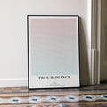 A framed True Romance movie script poster leaning against a wall in a minimalist interior.