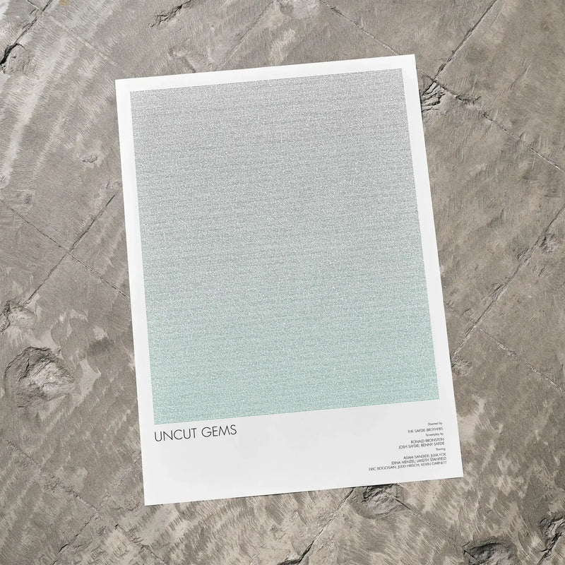A Uncut Gems movie script poster laid flat on a textured floor surface.